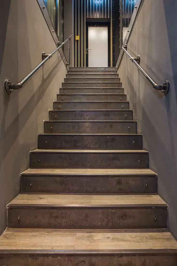 Gerade Treppe mit Holzstufen und Handlauf zwischen grauen Wänden