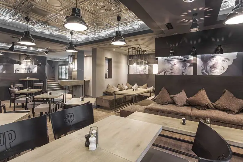 Lounge mit Sofa, Tischen und Stahlleuchten unter einer Decke aus Metallkassetten